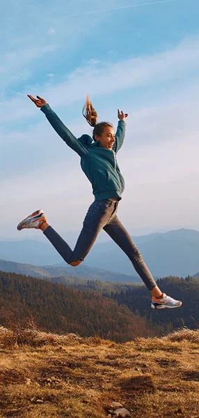 woman jumping in the air on top of a mountain