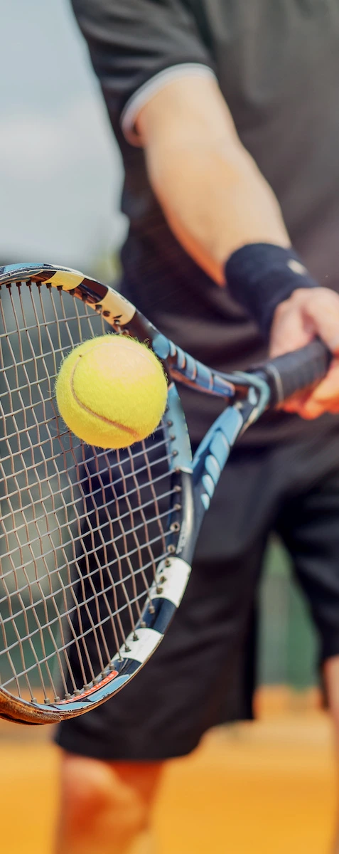 close up of a man hitting a tennis ball with racket